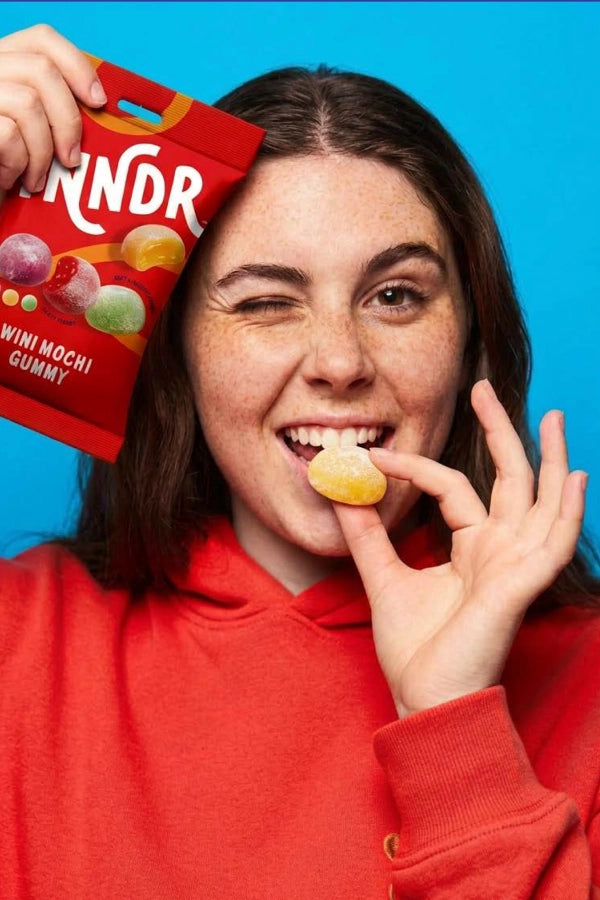 woman in red hoodie jacket holdling Go Wandr mini mochi gummies