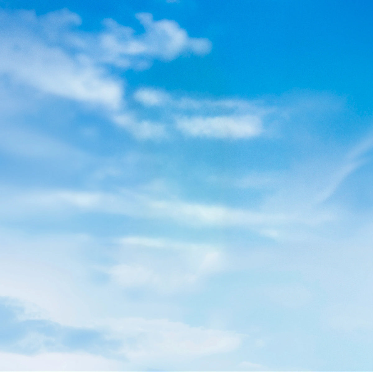 A soft blue sky with wispy white clouds drifting across the frame.