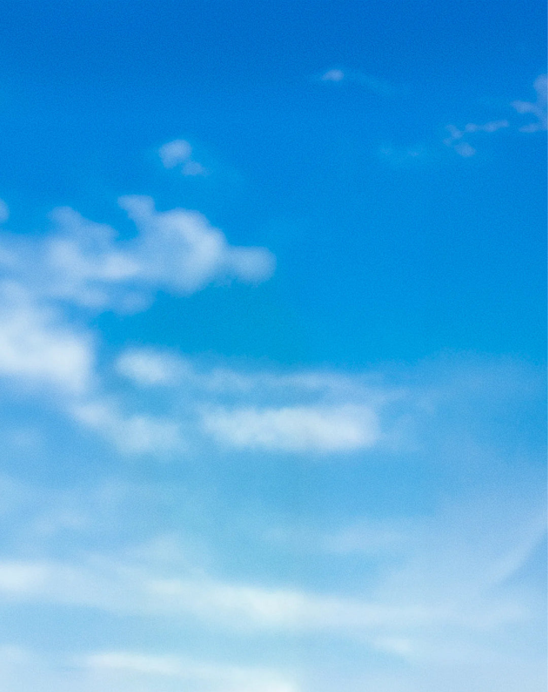 A bright blue sky with soft white clouds drifting across the frame.
