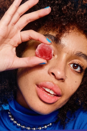 woman in blue shirt covering her eyes with a Go Wandr mini mochi gummy