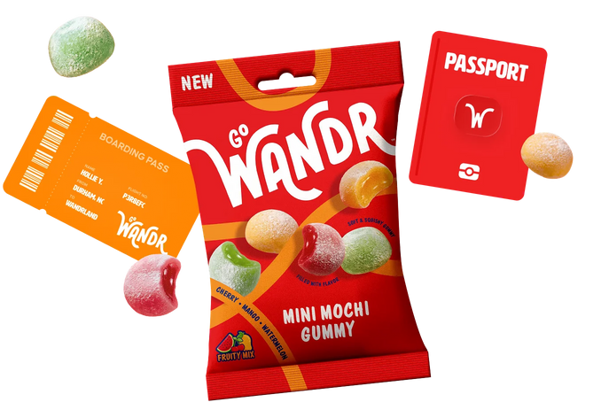 A red bag of Go Wander Mini Mochi Gummy candy is centered on a black background, surrounded by floating candy pieces and branded orange and red travel-themed cards. The packaging prominently shows the Go Wander brand and the flavor name Mini Mochi Gummy.