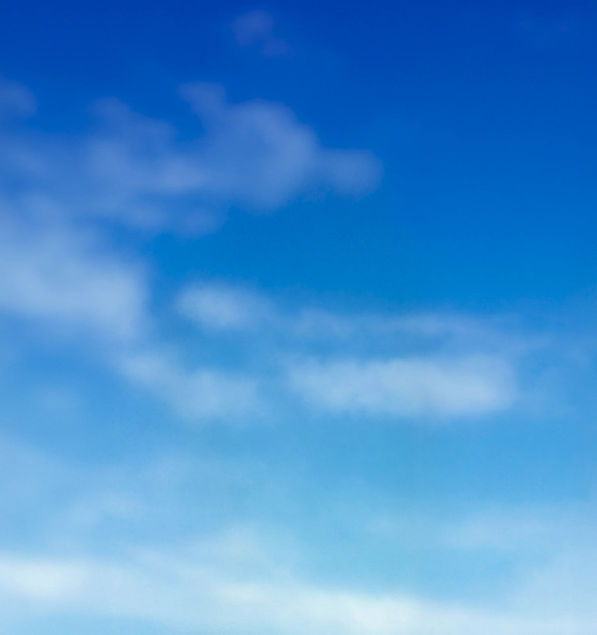 A bright blue sky with soft white clouds drifting across the frame.