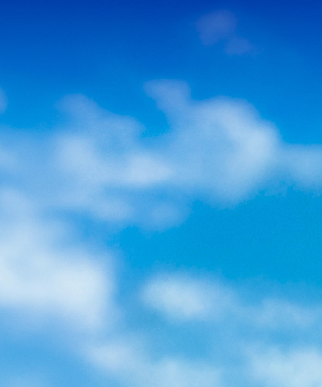 A soft-focus photograph of a bright blue sky with white clouds.
